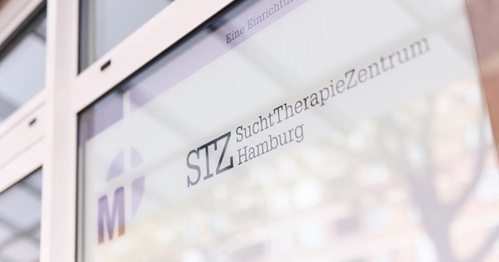 Fensterscheibe mit Aufschrift 'STZ SuchtTherapieZentrum Hamburg'. Sch?ne Spiegelung auf dem Glas mit leichter Unsch?rfe.