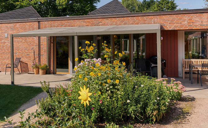 Moderner Backstein-Bungalow des Diakoniezentrums Rahlstedt mit bluehendem Garten an einem sonnigen Tag.