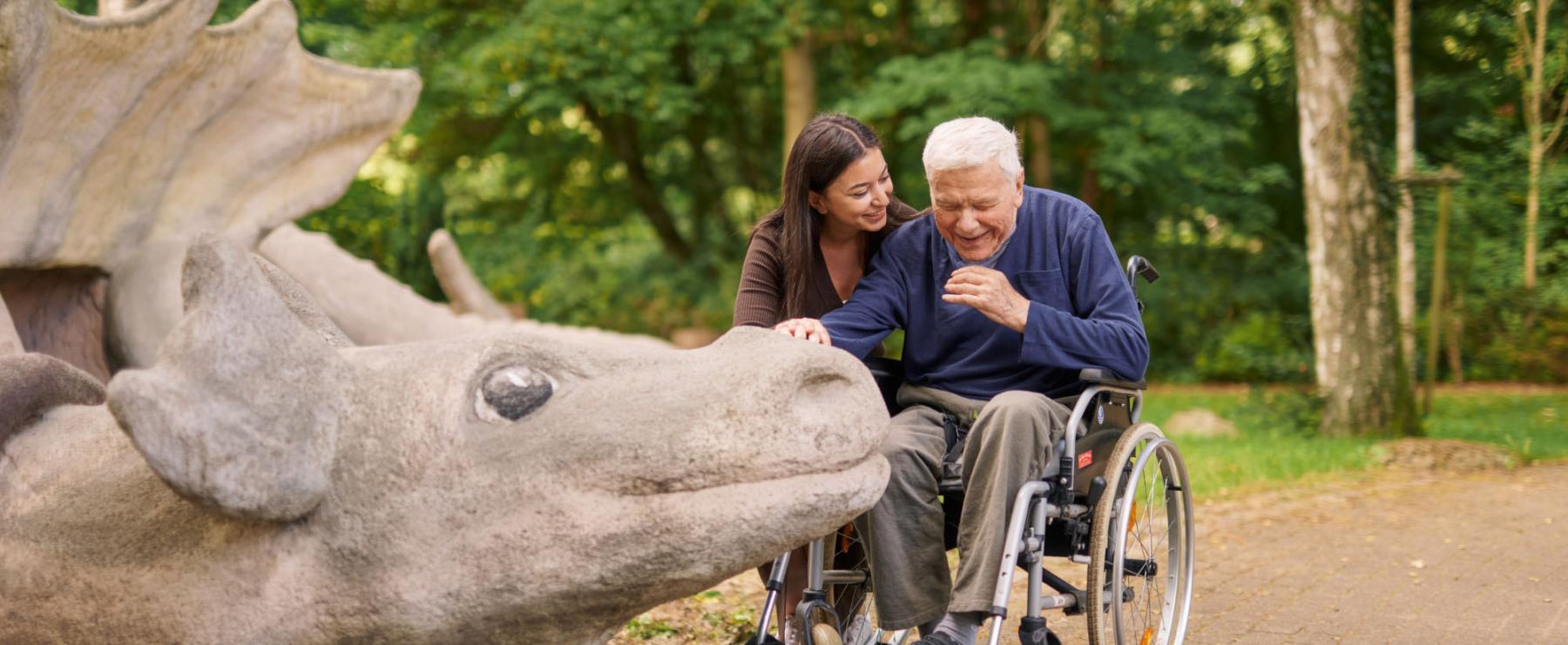 Ansicht eines modernen Geb?udes mit Balkonen, teilweise verdeckt durch das ?ppige, gr?ne Blattwerk eines Baumes.